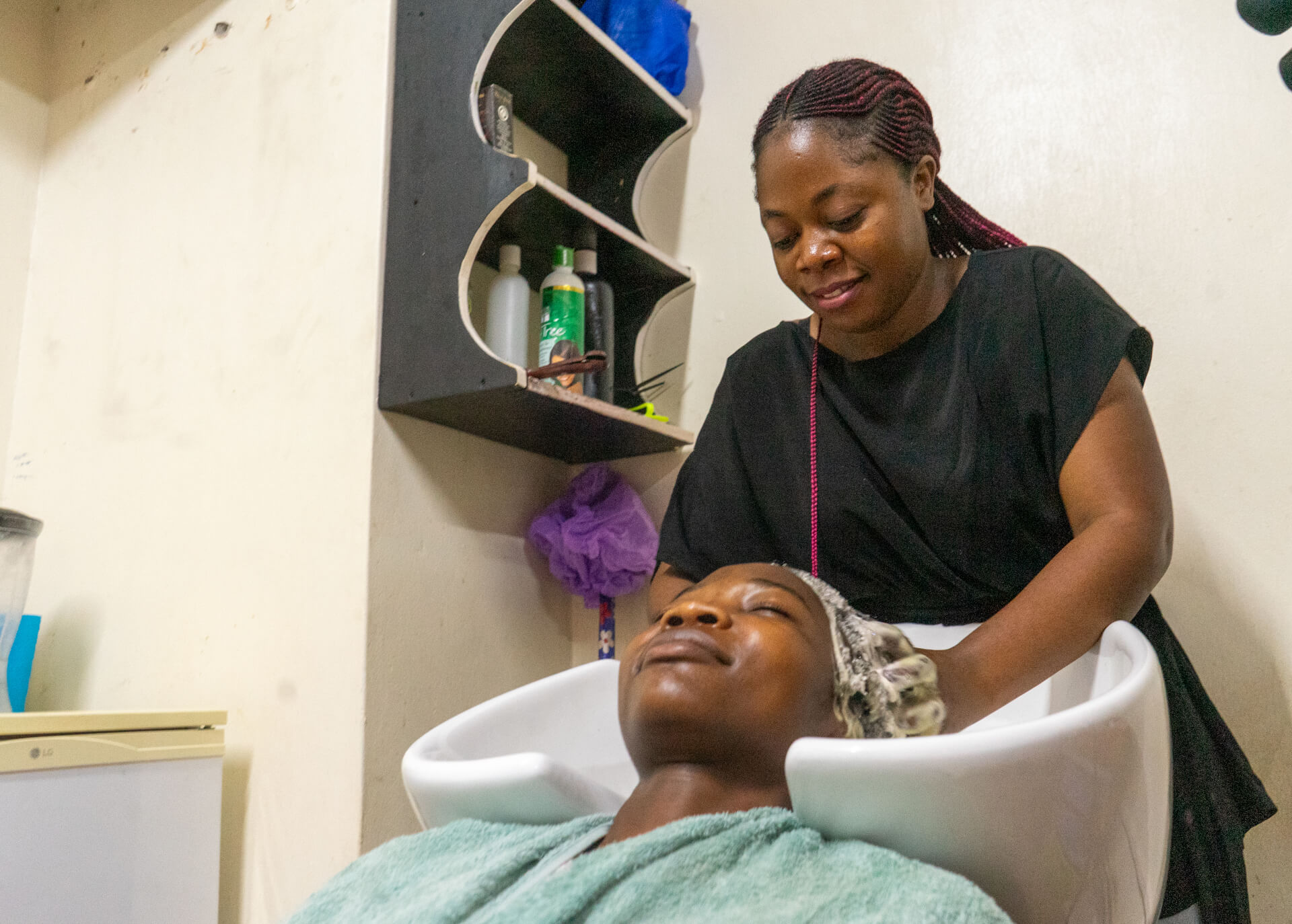 Elise Bakajika washing her client's hair in Kampala.